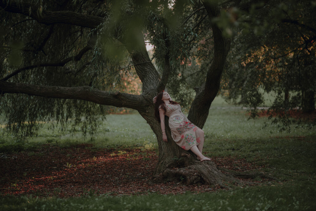 szamanka opierająca się o pień drzewa