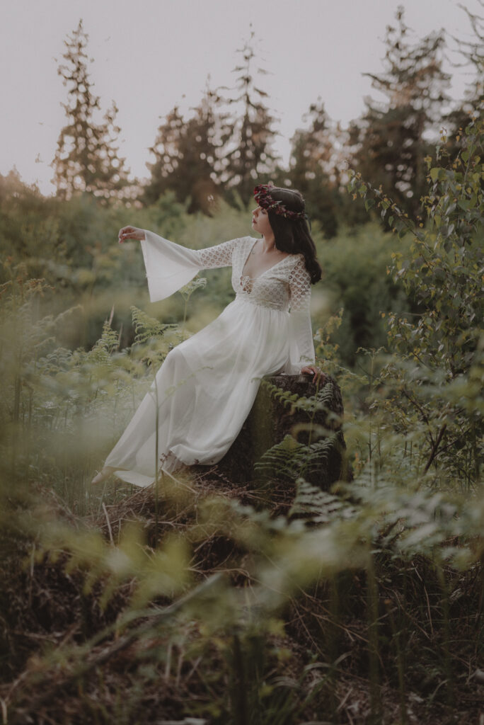 astrolog/tarocistka w białej sukni, z wiankiem z czerwonych kwiatów w lesie