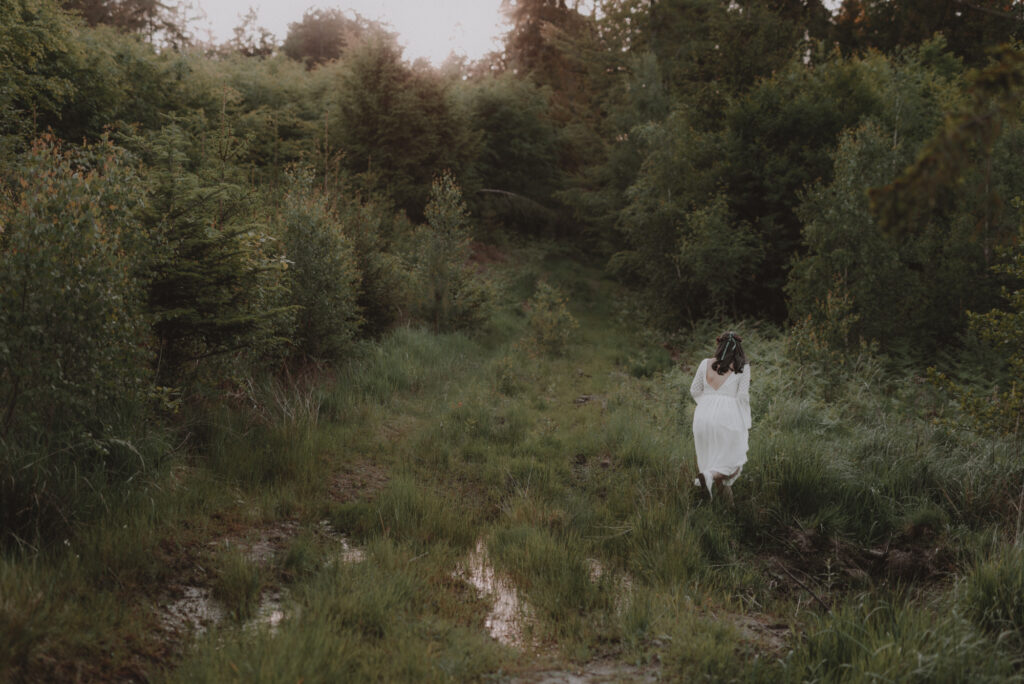 astrolog/tarocistka w białej sukni, z wiankiem z czerwonych kwiatów w lesie