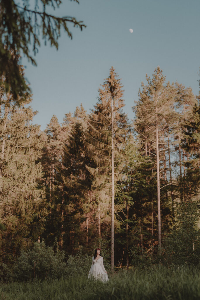 astrolog/tarocistka w białej sukni, z wiankiem z czerwonych kwiatów w lesie