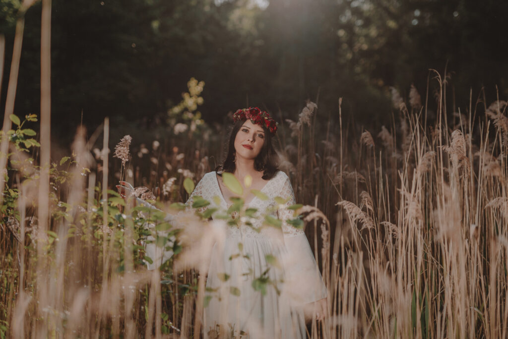 astrolog/tarocistka w białej sukni, z wiankiem z czerwonych kwiatów w lesie
