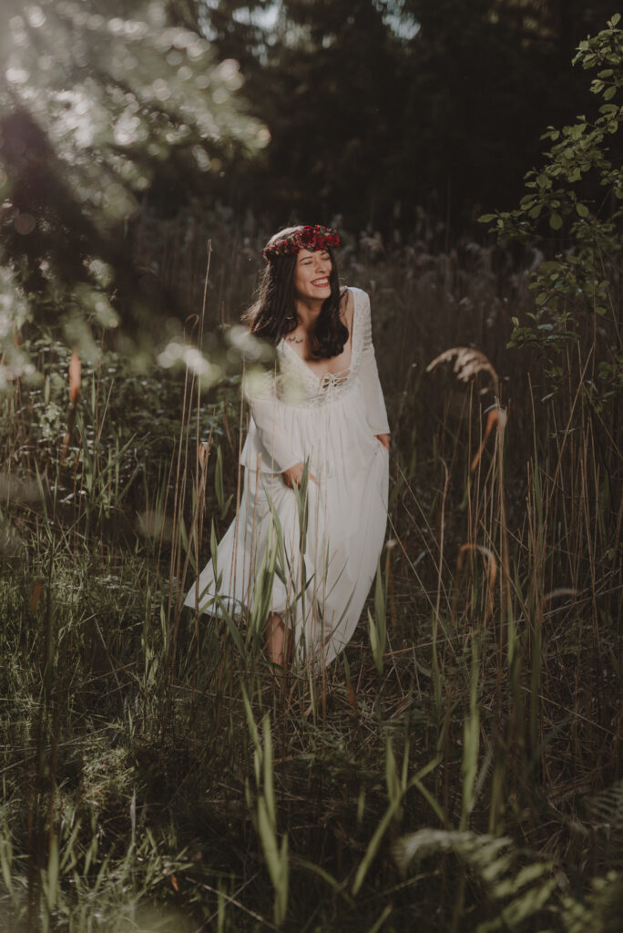astrolog/tarocistka w białej sukni, z wiankiem z czerwonych kwiatów w lesie