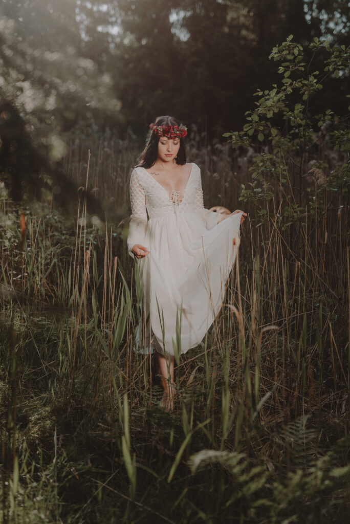 astrolog/tarocistka w białej sukni, z wiankiem z czerwonych kwiatów w lesie