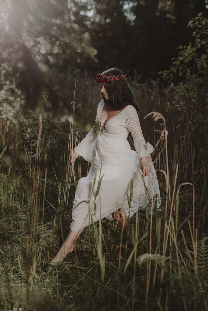 astrolog/tarocistka w białej sukni, z wiankiem z czerwonych kwiatów w lesie