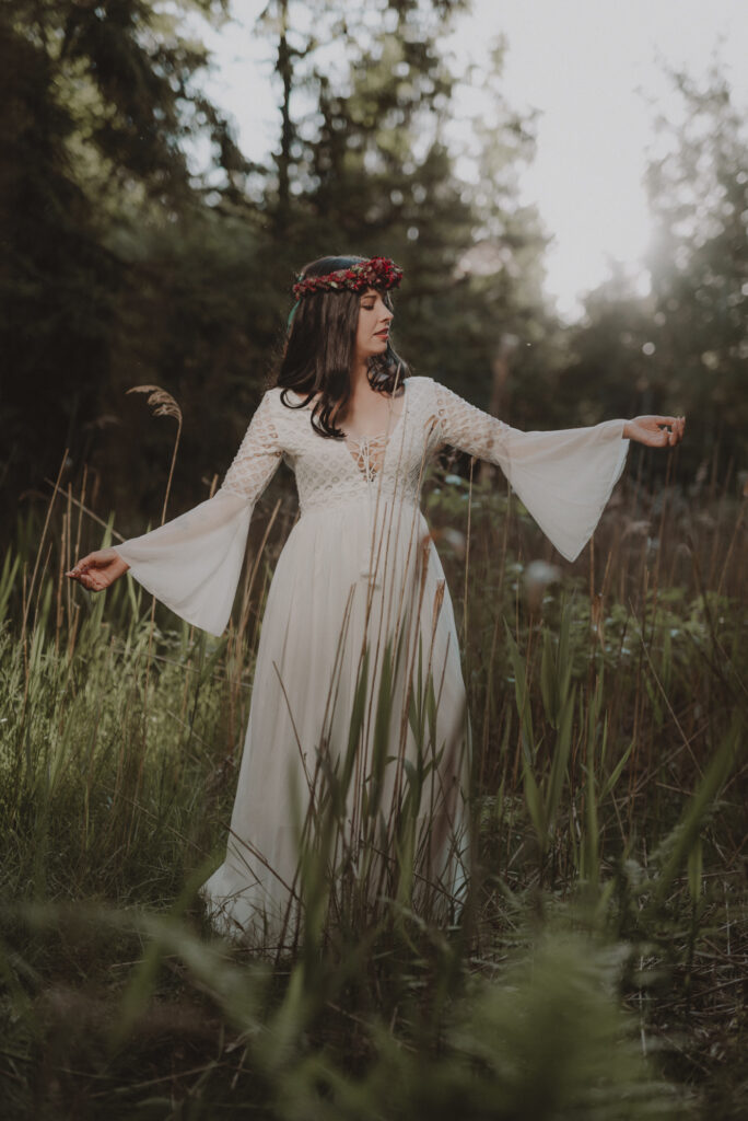 astrolog/tarocistka w białej sukni, z wiankiem z czerwonych kwiatów w lesie
