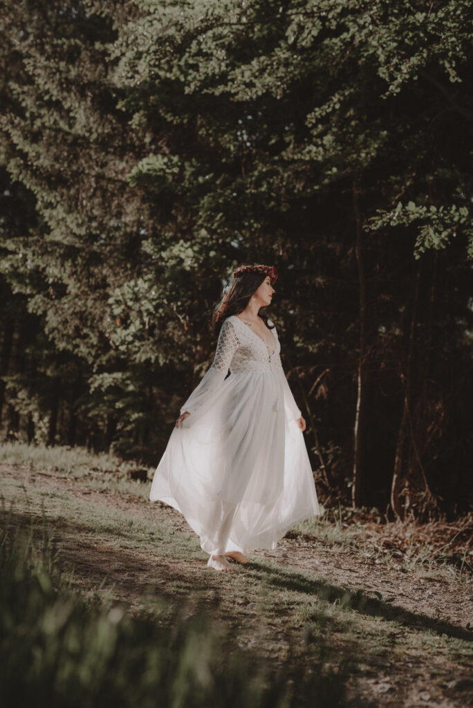 astrolog/tarocistka w białej sukni, z wiankiem z czerwonych kwiatów w lesie