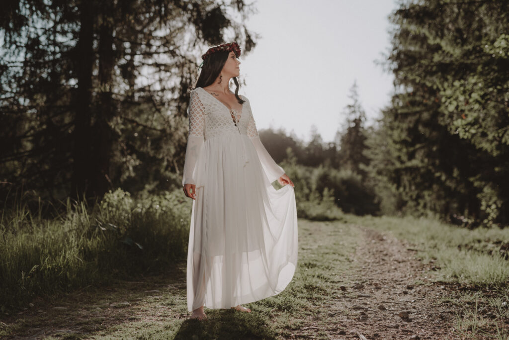 astrolog/tarocistka w białej sukni, z wiankiem z czerwonych kwiatów w lesie