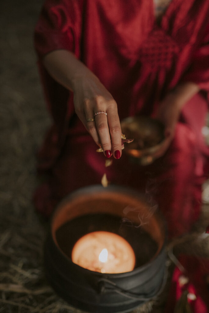 dłoń wrzucająca płatki róż do świecy