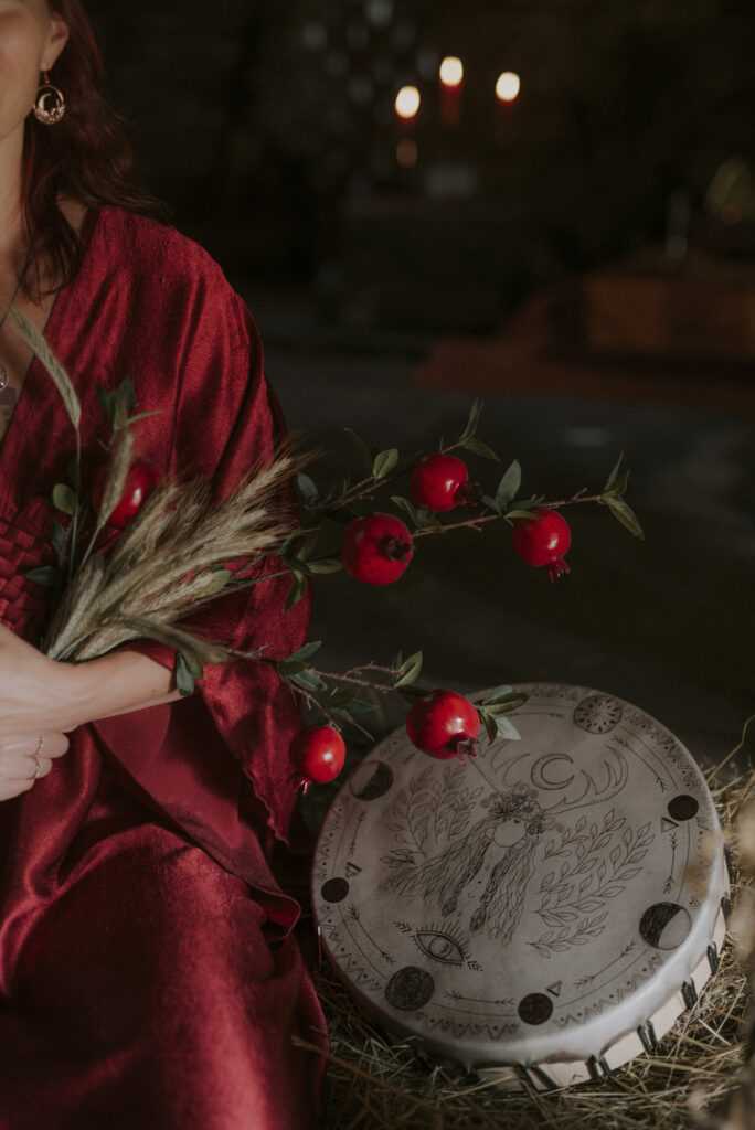 kobieta wiedźma w czerwonej szacie podczas święta lammas, a obok bęben rytualny